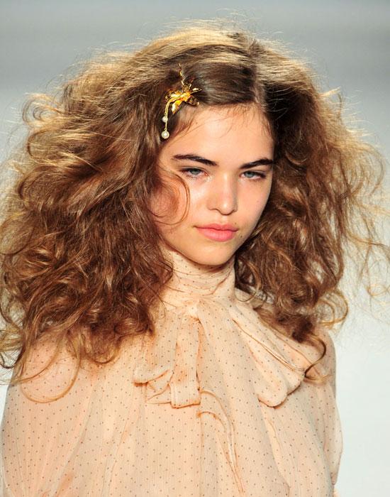 For more of a wild mood, tighten those curls up and add volume with  a strong hairspray (Accessorizing the look with a pin adds a nice touch. 